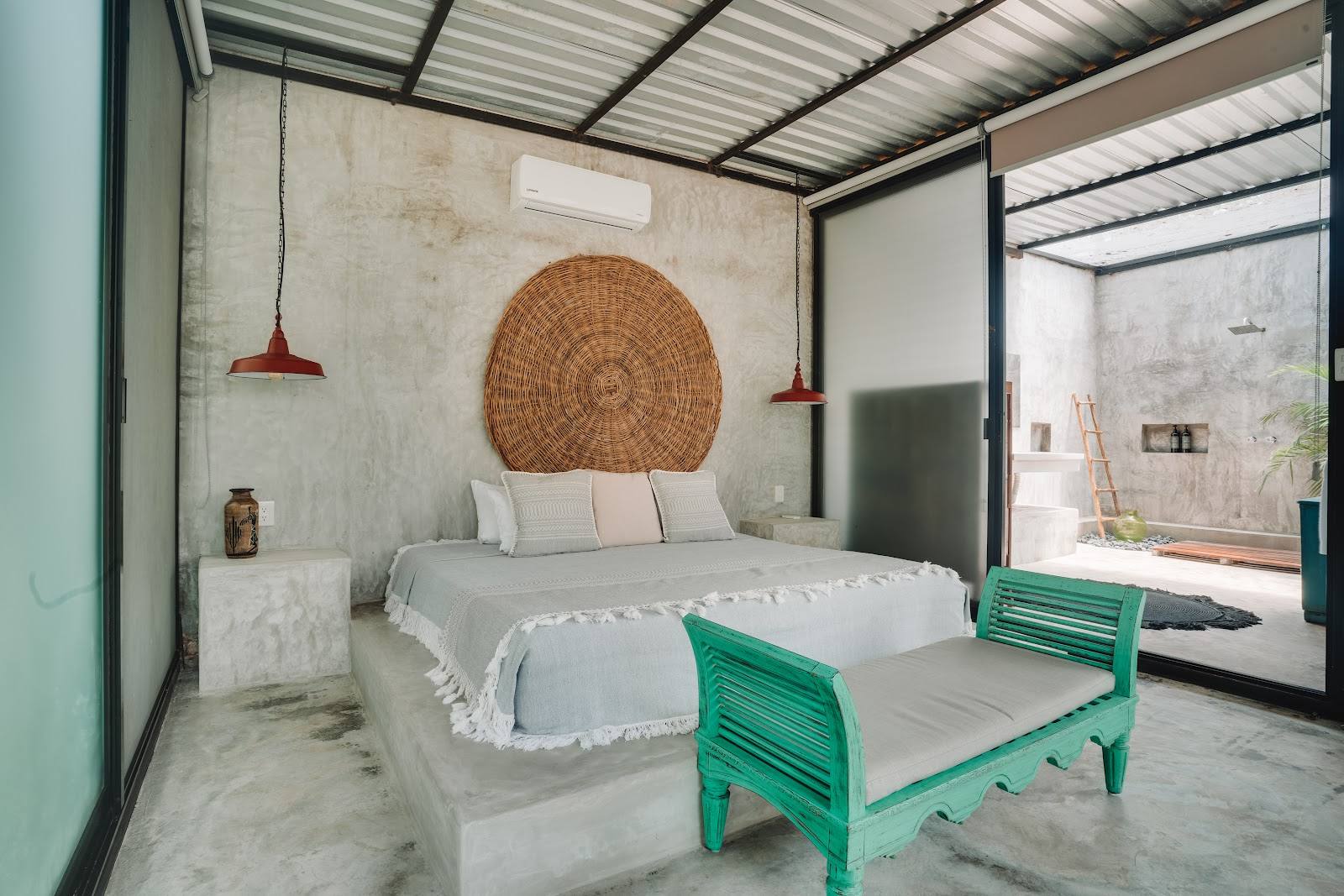 A bedroom with a turquoise bench and an open shower