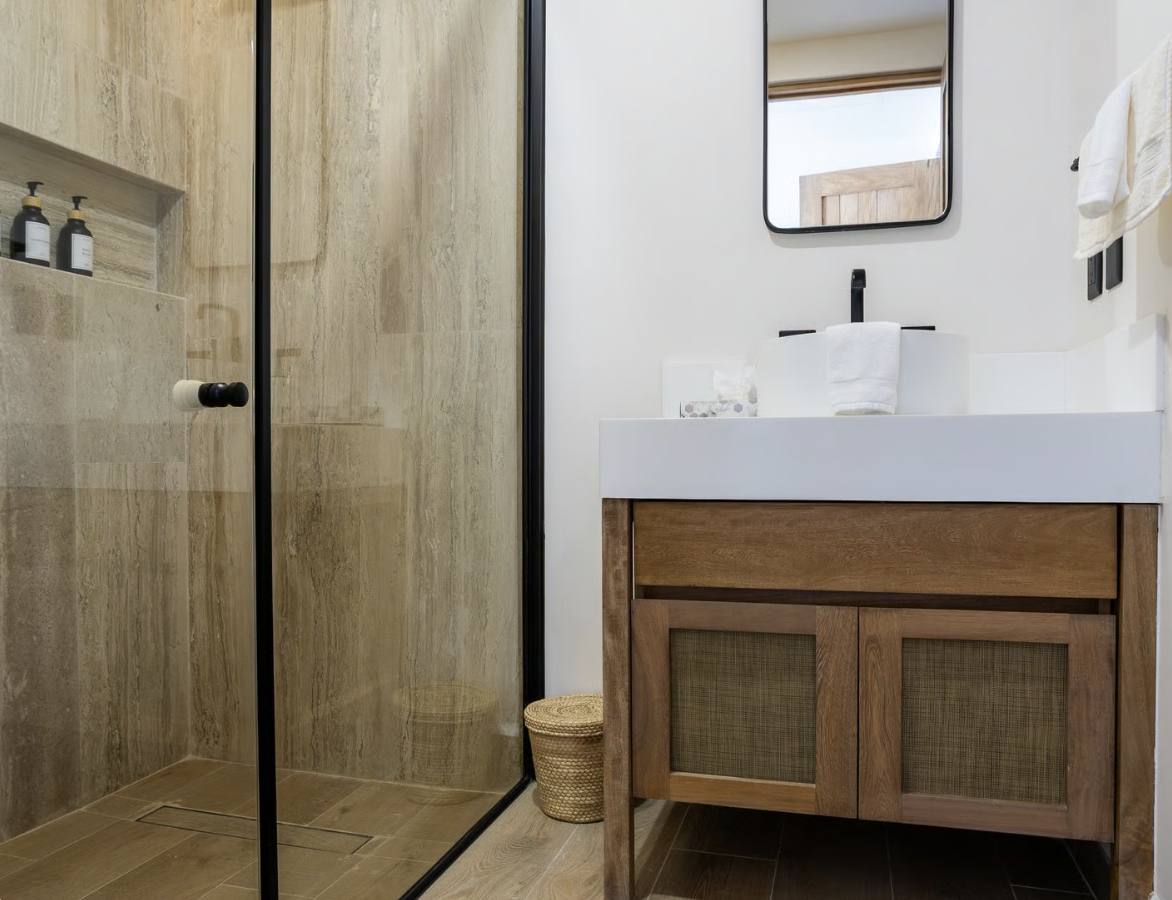 A bathroom with a glass shower and a wooden vanity