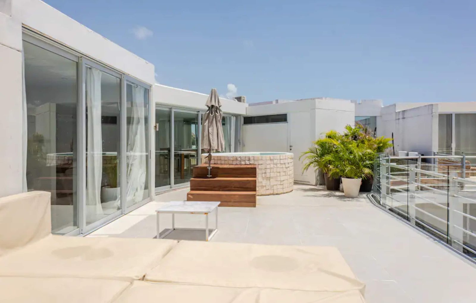 Rooftop terrace with a hot tub and lounge beds