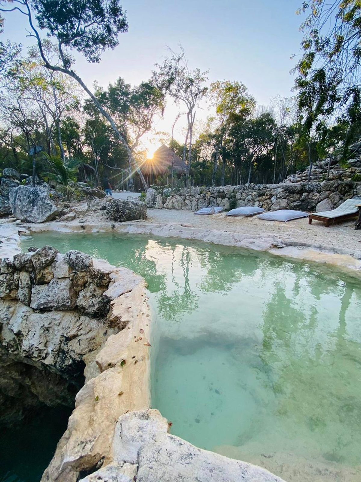 The natural pool with the late sun through the trees