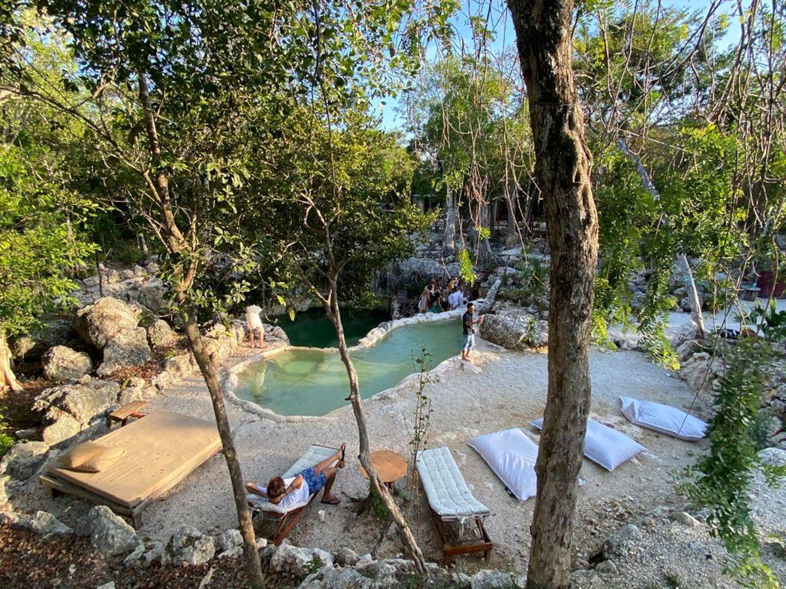 Loungers and cushions by the natural pool among the trees