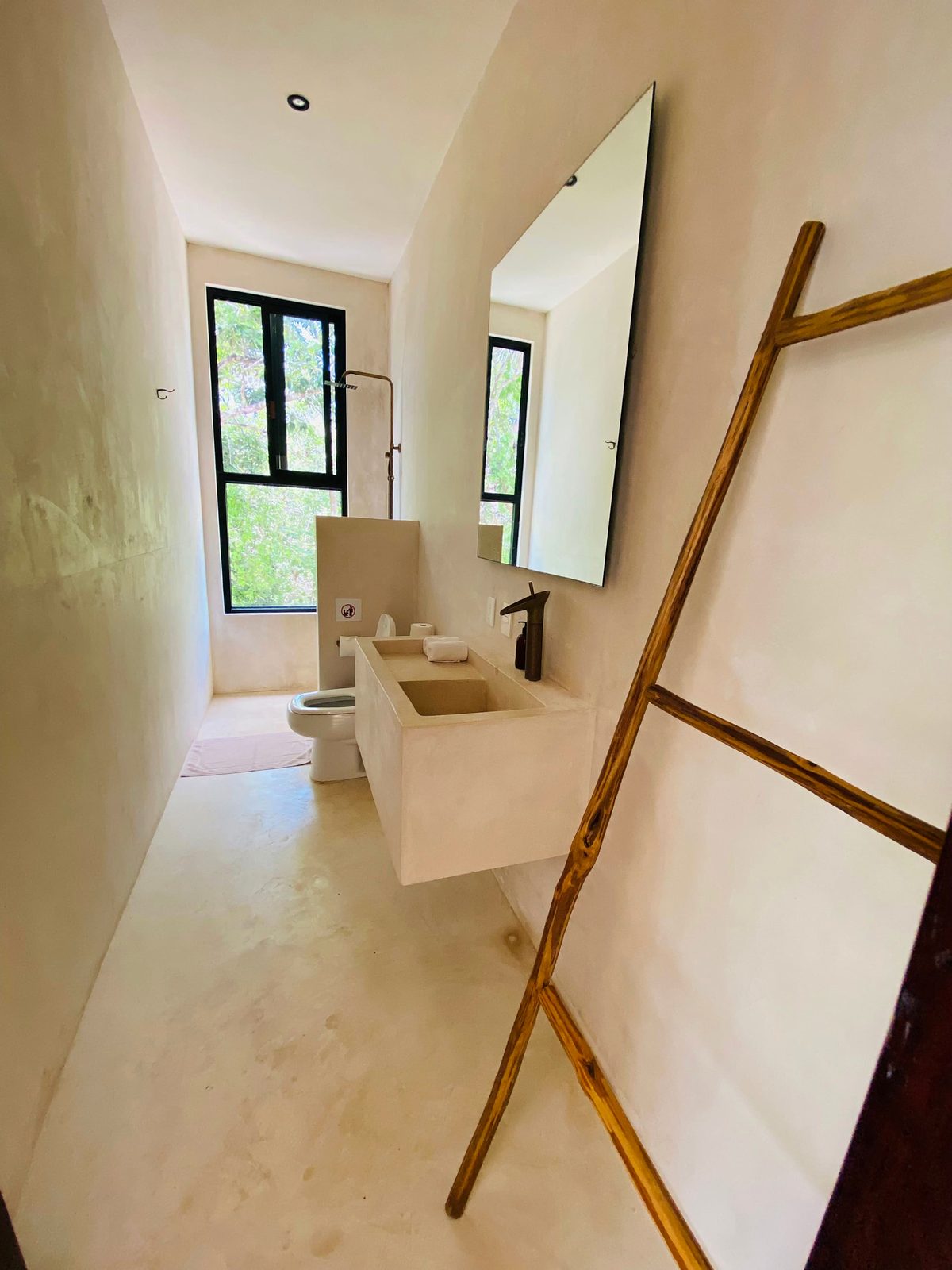 A suite bathroom with stone basin and a window to the trees