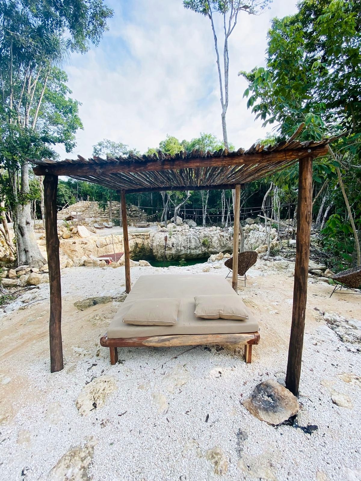 A shaded daybed on the white sand by the cenote