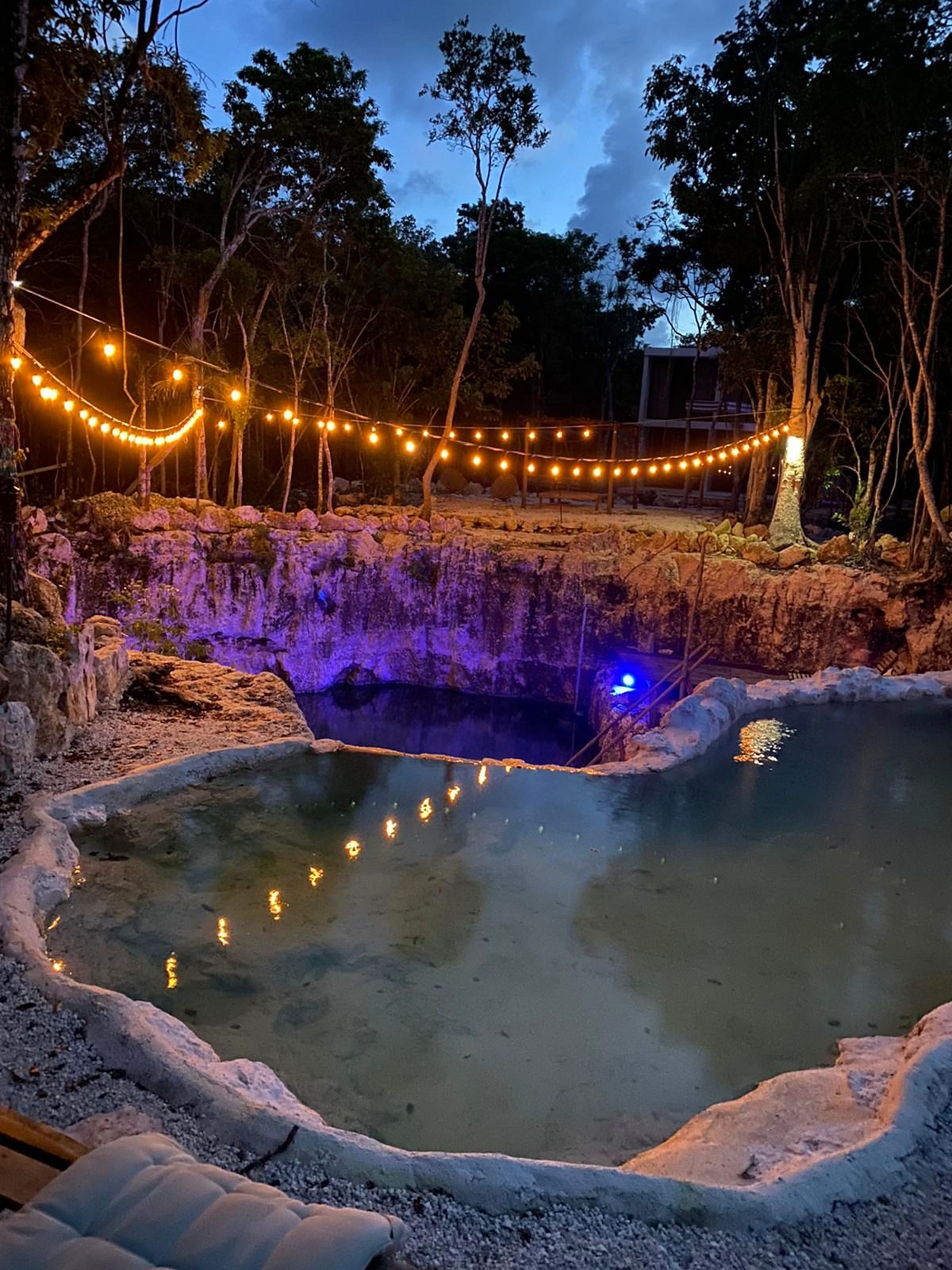 The natural pool at night under string lights