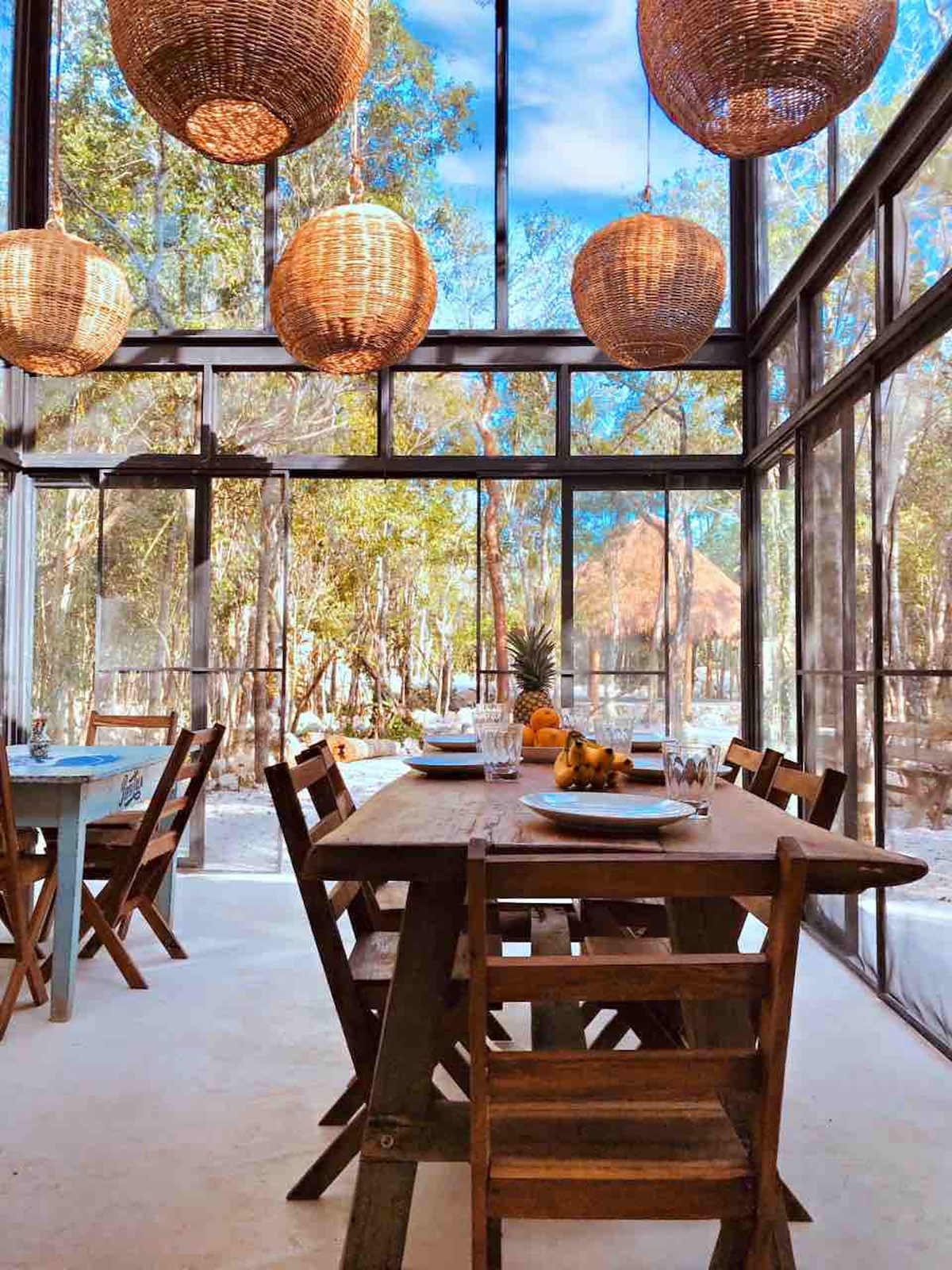 The glass dining pavilion with woven lamps among the trees