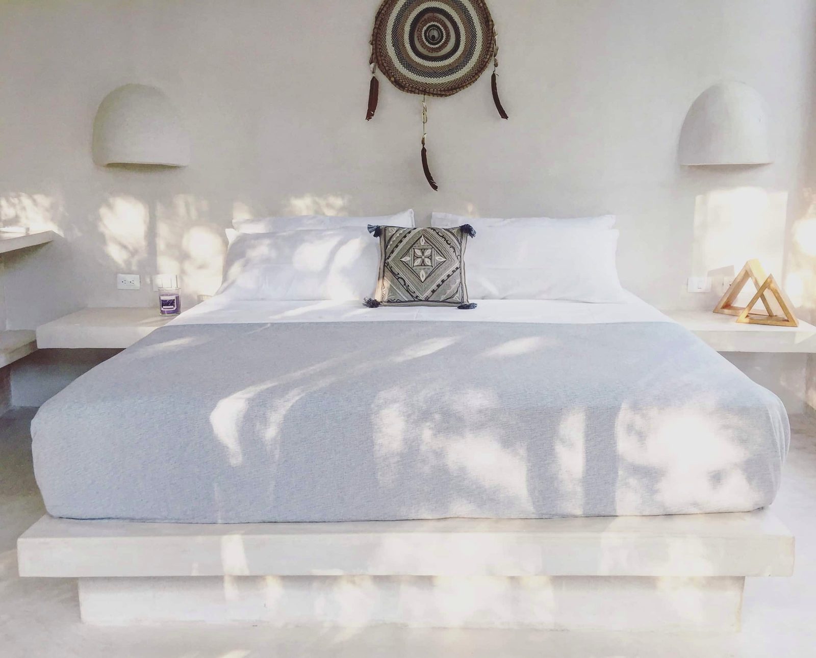 A king bed in a white suite with soft morning light