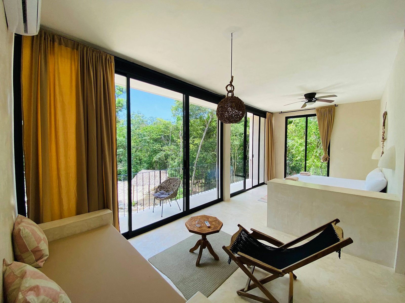 A suite with a sitting area and floor-to-ceiling windows to the jungle