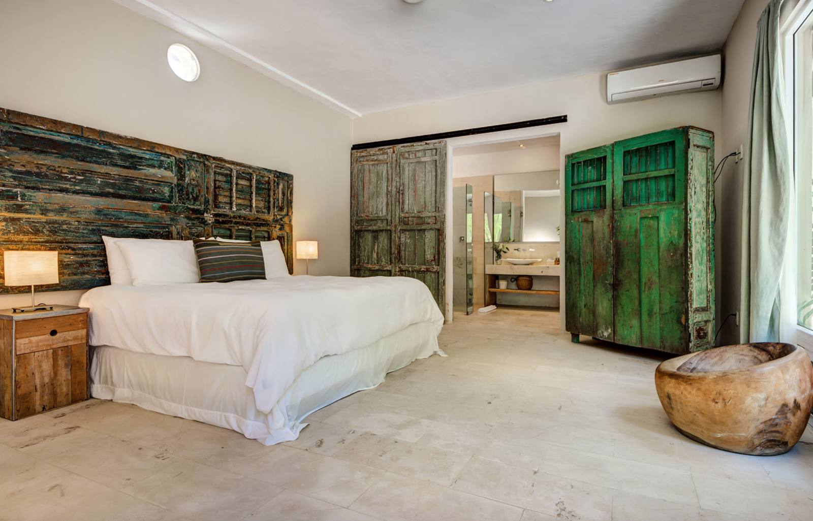 A bedroom with a green armoire and a wooden stool