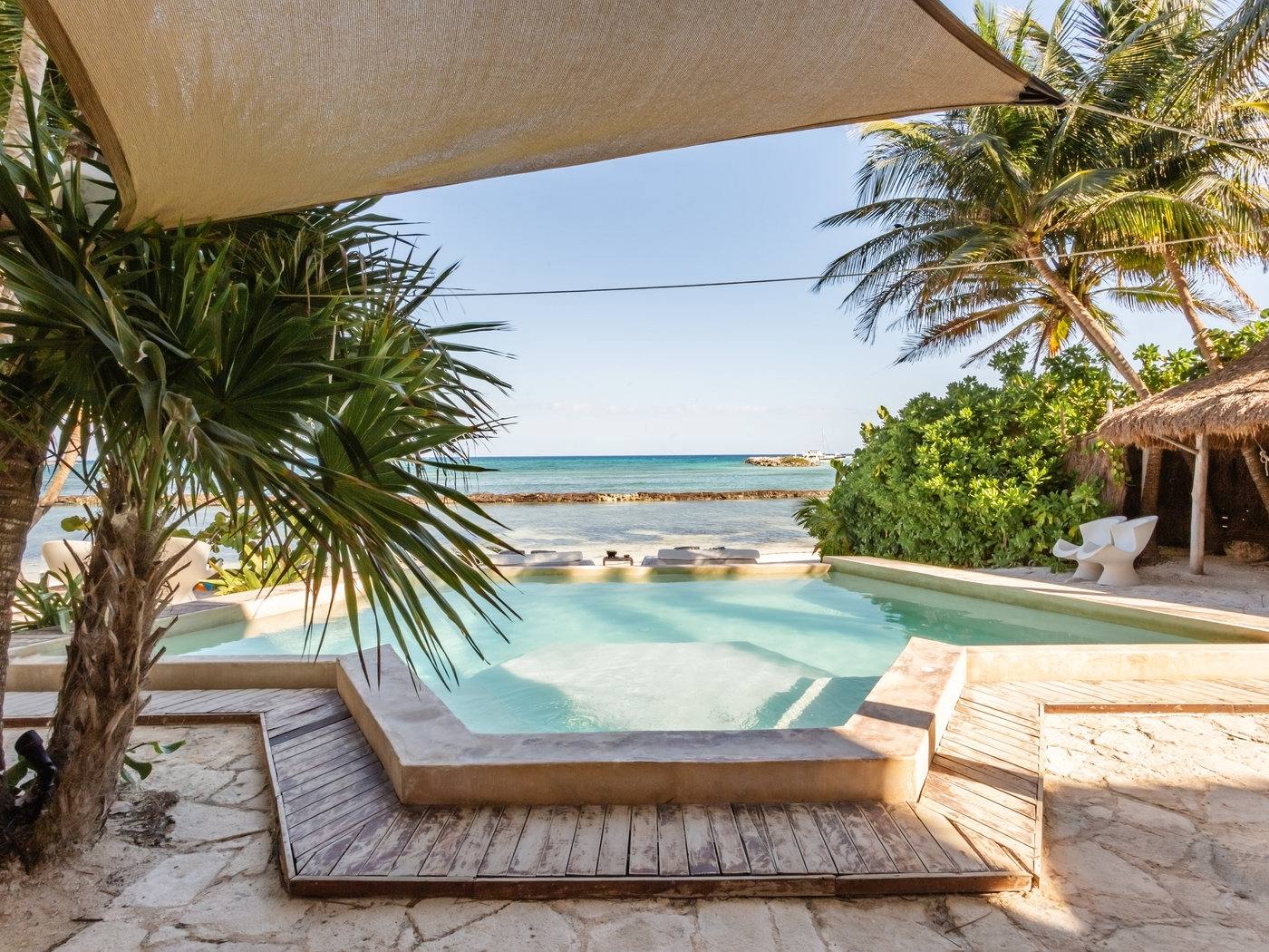 The pool and deck under a shade sail, facing the sea
