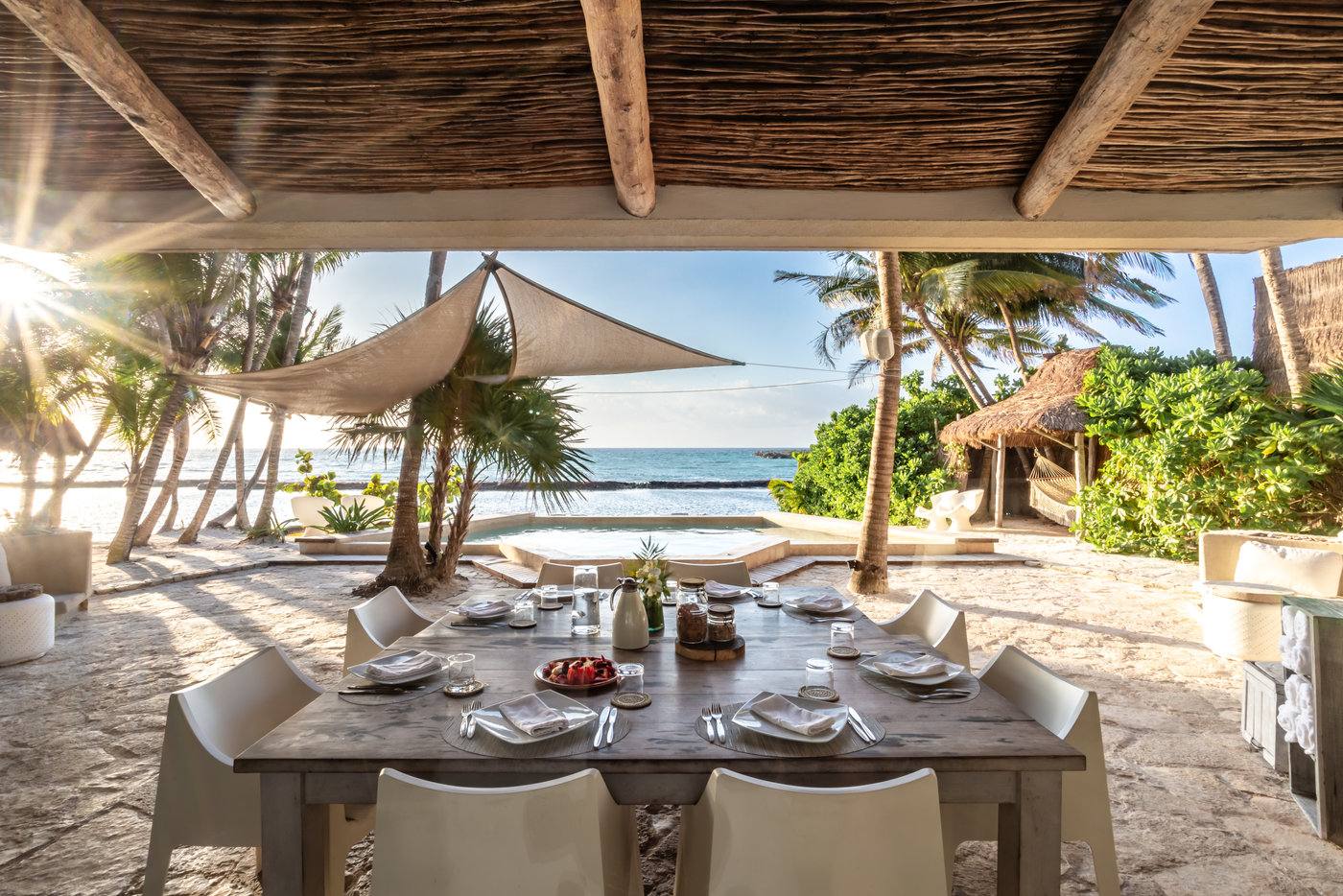 The table set under the palapa with the beach ahead