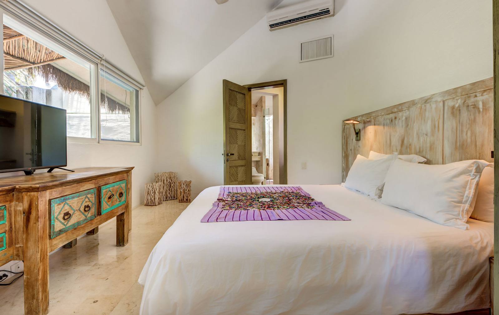 A bedroom with a reclaimed-wood headboard