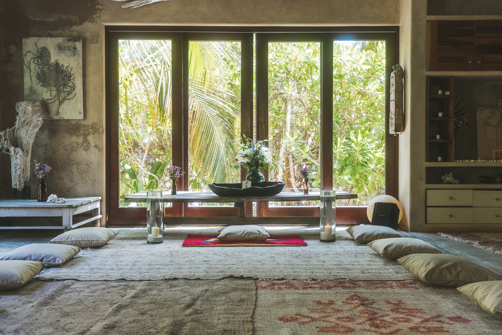 The living room with floor cushions and windows to the garden
