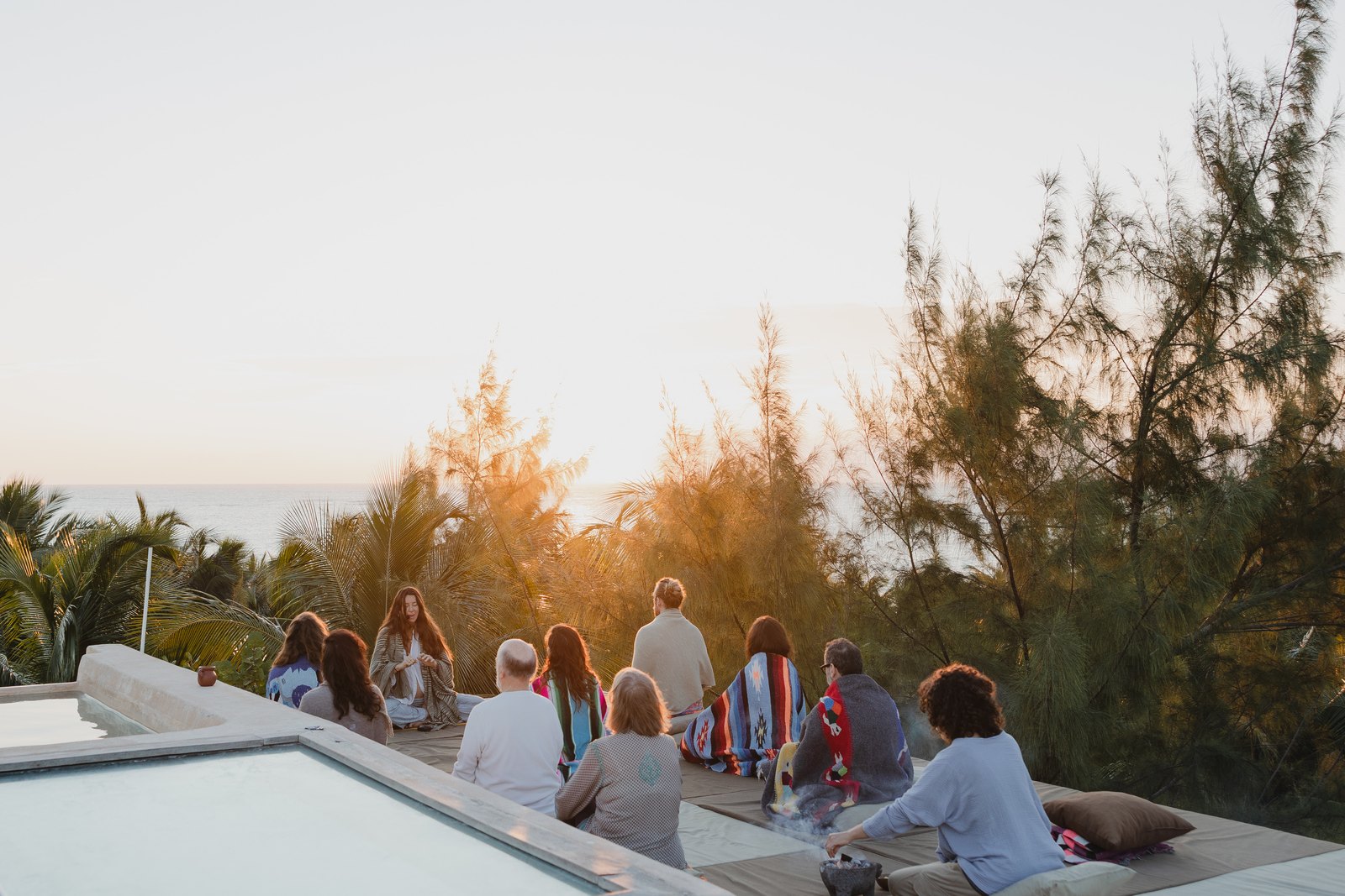 A group meditating on the rooftop at sunset