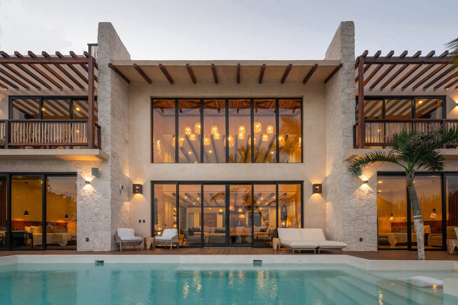 The house lit at dusk above the pool